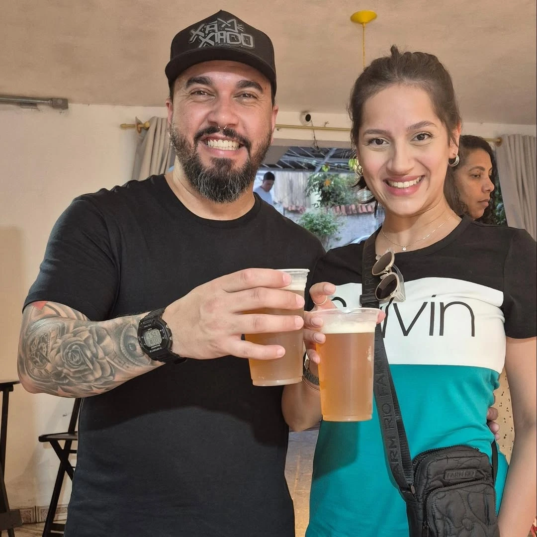 Brinde a dois no Quintal da Carolina, com copos de cerveja artesanal.